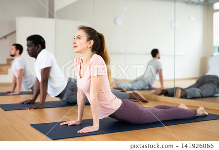 Sporty girl performing Urdhva Mukha Shvanasana during group yoga training 141926066
