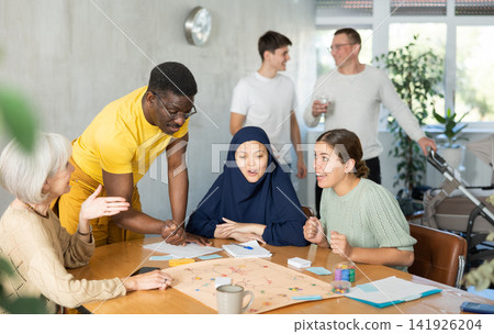 Group of multinational people playing board game 141926204