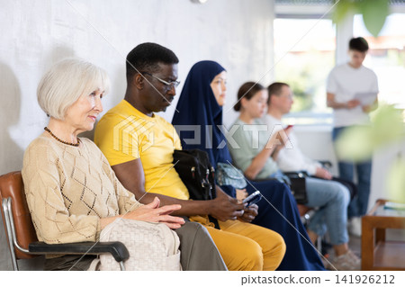 Positive elderly woman sitting in lobby of medical clinic Positive elderly woman sitting in lobby of medical clinic 141926212