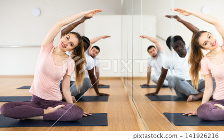 Woman and men practising lotus pose exercises Woman and men practising lotus pose exercises 141926216