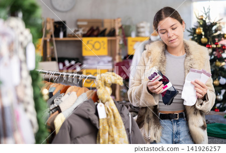 Young girl near showcase pick out and buying socks, New Year eve Young girl near showcase pick out and buying socks, New Year eve 141926257