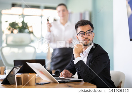 Male and female colleagues are watching presentation in office Male and female colleagues are watching presentation in office 141926335