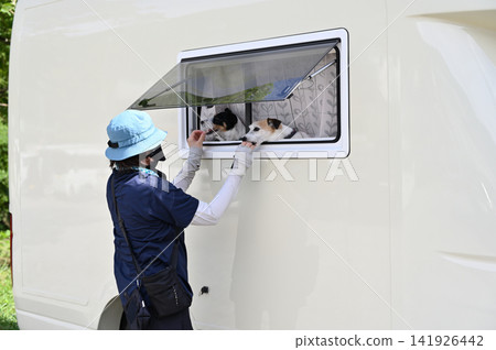 一位女士喜歡帶著她的狗——傑克羅素梗犬——開著露營車去露營。 一位女士喜歡帶著她的狗——傑克羅素梗犬——開著露營車去露營。 141926442