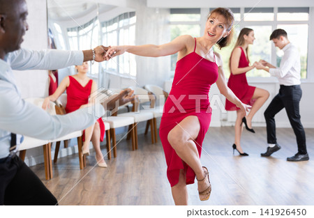 Woman in red practicing vigorous dance with partner in choreography class 141926450