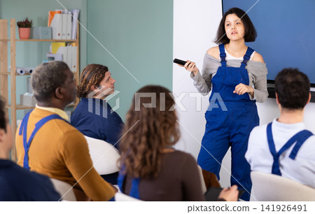 Young woman worker gives lecture in auditorium Young woman worker gives lecture in auditorium 141926491