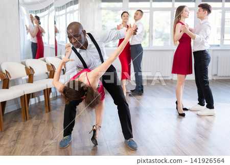 African American practicing bachata with brunette in red in dance class African American practicing bachata with brunette in red in dance class 141926564