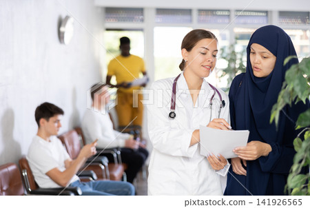 Nurse discusses documents with young Asian woman in veil 141926565