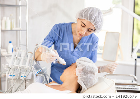 Female aesthetician applying atomized nutrients onto woman client face Female aesthetician applying atomized nutrients onto woman client face 141926579