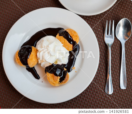 Profiteroles served with topping for dessert Profiteroles served with topping for dessert 141926581