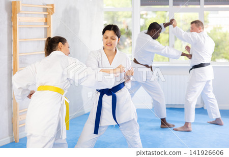 Block, then strike. Shot of two female martial artists practicing karate in gym Block, then strike. Shot of two female martial artists practicing karate in gym 141926606