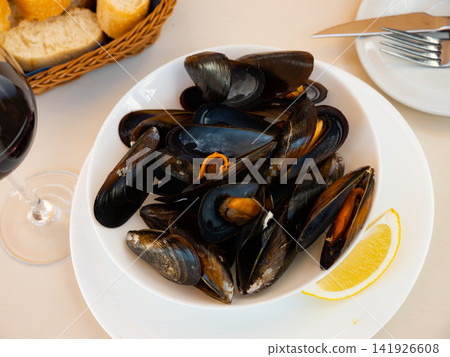 Gourmet seafood tapas. Steam cooked mussels garnished with lemon slice on plate Gourmet seafood tapas. Steam cooked mussels garnished with lemon slice on plate 141926608