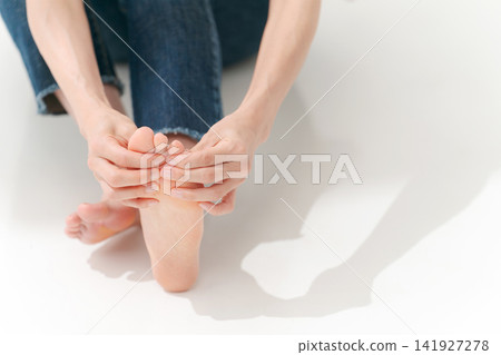 一個女人在摸自己的腳趾 一個女人在摸自己的腳趾 141927278
