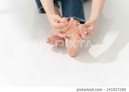 一個女人在摸自己的腳趾 一個女人在摸自己的腳趾 141927280