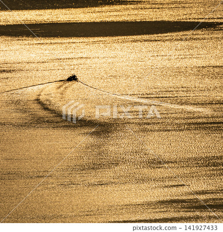 The surface of Lake Biwa, shining golden in the morning sun, and the silhouette of a fishing boat. The surface of Lake Biwa, shining golden in the morning sun, and the silhouette of a fishing boat. 141927433