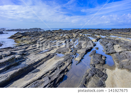 On a clear summer morning, the scenery of the curved, ridge-like rock formations and tidal pools reflecting the blue sky at Hinadan on Jogashima Island. On a clear summer morning, the scenery of the curved, ridge-like rock formations and tidal pools reflecting the blue sky at Hinadan on Jogashima Island. 141927675