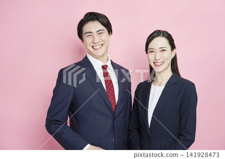 Portraits of a businessman and businesswoman against a pink background, looking directly at the camera. Portraits of a businessman and businesswoman against a pink background, looking directly at the camera. 141928473