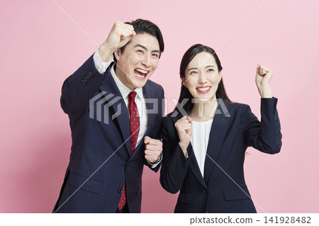 一位商人和一位女商人以粉紅色背景擺出勝利姿勢。 141928482