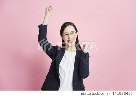 Businesswoman making a victory pose against a pink background Businesswoman making a victory pose against a pink background 141928495