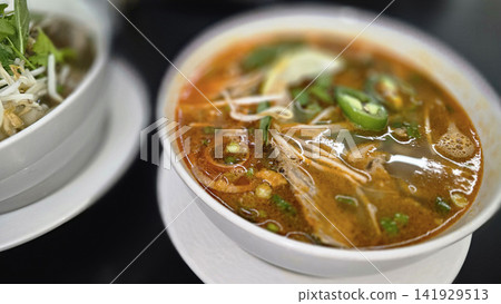Vietnamese Pho Noodle Soup With Fresh Herbs, Lime And Crispy Spring Rolls On Table Vietnamese Pho Noodle Soup With Fresh Herbs, Lime And Crispy Spring Rolls On Table 141929513
