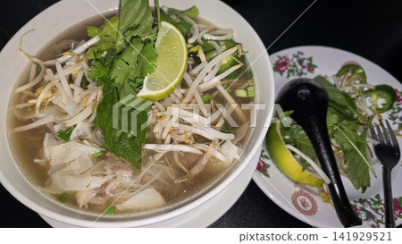 Vietnamese Pho Noodle Soup With Fresh Herbs, Lime And Crispy Spring Rolls On Table Vietnamese Pho Noodle Soup With Fresh Herbs, Lime And Crispy Spring Rolls On Table 141929521