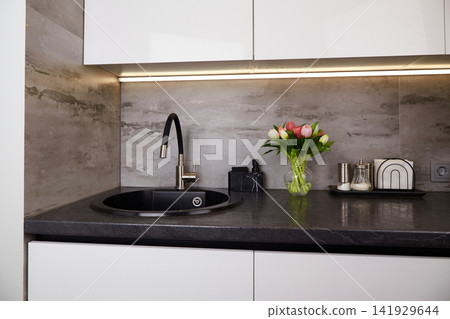 A kitchen scene shows a black sink next to a bouquet of flowers.  141929644