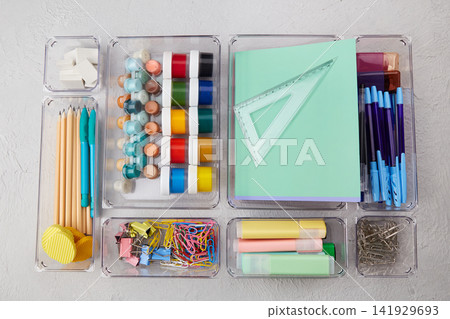 School supplies are laid out on a wooden table in transparent containers. School supplies are laid out on a wooden table in transparent containers. 141929693
