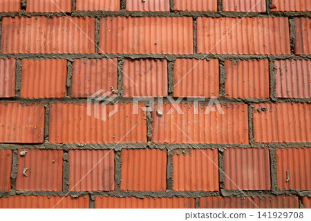 Brick wall construction with red clay bricks during daylight at a construction site Brick wall construction with red clay bricks during daylight at a construction site 141929708