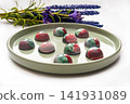 Collectible handmade tempered chocolate candies with a glossy painted body on a round plate with a blurred background and bokeh elements 141931089