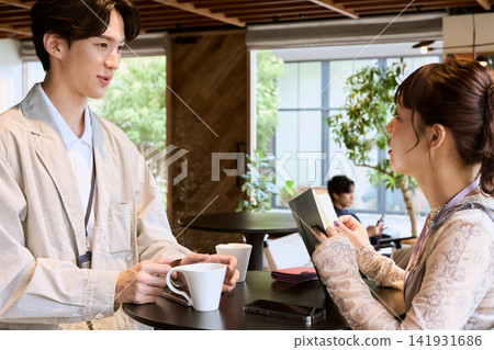 Businessmen and businesswomen chatting while drinking coffee in a cafe space. Businessmen and businesswomen chatting while drinking coffee in a cafe space. 141931686