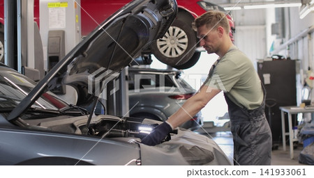 Repairman working on an usual car maintenance. Professional mechanic is working on a car in a car service. Repairman working on an usual car maintenance. Professional mechanic is working on a car in a car service. 141933061