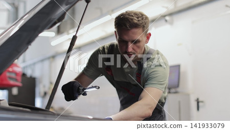 Repairman working on an usual car maintenance. Professional mechanic is working on a car in a car service. Repairman working on an usual car maintenance. Professional mechanic is working on a car in a car service. 141933079