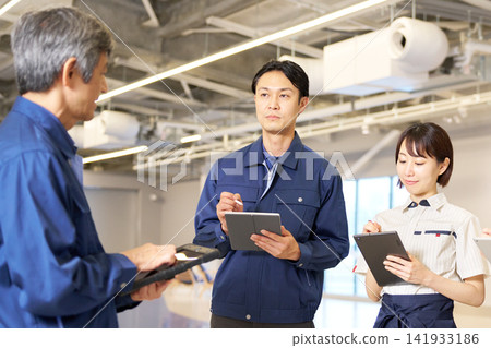 男女員工一邊聽老闆講話,一邊拿著平板電腦。 男女員工一邊聽老闆講話,一邊拿著平板電腦。 141933186