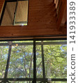 The summer greenery and the warmth of wood visible from the window of the wooden lodge. 141933389