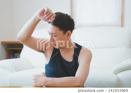 一名40歲的男子在客廳用男士除臭劑檢查腋下氣味。 一名40歲的男子在客廳用男士除臭劑檢查腋下氣味。 141933969