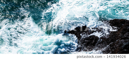 A view of the rocky reefs and the rough sea with white waves from atop a cliff. A view of the rocky reefs and the rough sea with white waves from atop a cliff. 141934026