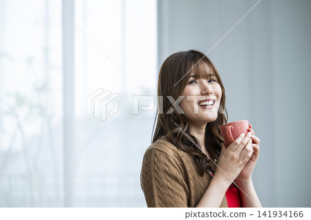 Young woman drinking coffee by the window Young woman drinking coffee by the window 141934166