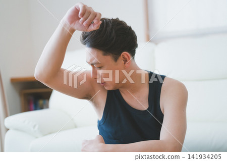 A 40-year-old man furrows his brow to check for underarm odor - Men's body care A 40-year-old man furrows his brow to check for underarm odor - Men's body care 141934205