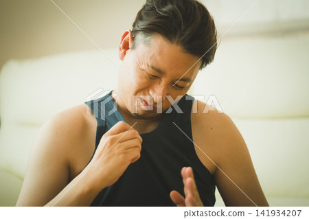 一位40歲的男子皺著眉頭檢查自己衣服上的氣味;這是男人對體味的擔憂。 一位40歲的男子皺著眉頭檢查自己衣服上的氣味;這是男人對體味的擔憂。 141934207