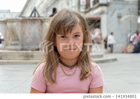 Serious young girl looking at camera in an urban square outdoors Serious young girl looking at camera in an urban square outdoors 141934801