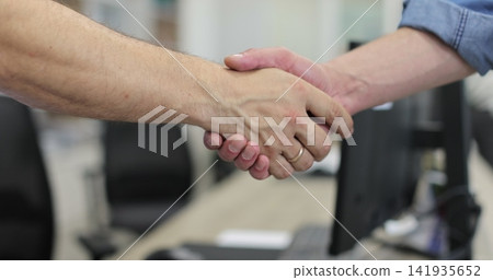 Car repair shop manager shakes hands with a customer who brought their car to the service center. Automotive industry, auto care, service. Car repair shop manager shakes hands with a customer who brought their car to the service center. Automotive industry, auto care, service. 141935652
