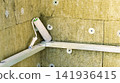 A roller and tray are placed on a support in a room with textured walls. The walls show signs of preparation for painting. The scene is part of a renovation 141936415