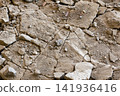 Cracked soil shows large broken pieces and small stones scattered across the ground in a dry area. The earth appears arid and tough 141936416