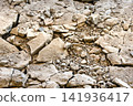 The ground has many cracks with broken pieces of rocks scattered around. The surface shows signs of erosion. It is daytime in a rugged area 141936417