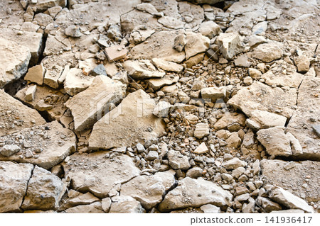 The ground has many cracks with broken pieces of rocks scattered around. The surface shows signs of erosion. It is daytime in a rugged area The ground has many cracks with broken pieces of rocks scattered around. The surface shows signs of erosion. It is daytime in a rugged area 141936417