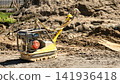 A machine is processing soil on a construction site. The area is busy with dirt and construction materials. Workers may be preparing for a new project 141936418