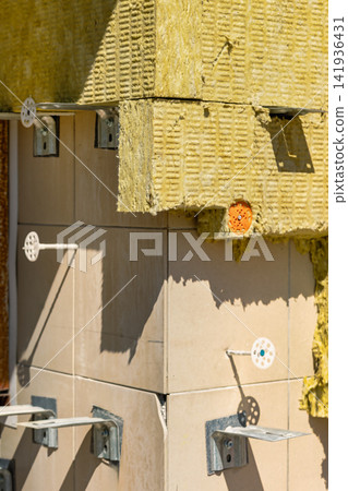 Workers are using insulation and tiles for a construction project at a building site. Tools and materials are visible on the exterior of the structure Workers are using insulation and tiles for a construction project at a building site. Tools and materials are visible on the exterior of the structure 141936431