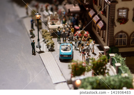 Miniature street scene with blue convertible and crowd outside building Miniature street scene with blue convertible and crowd outside building 141936483
