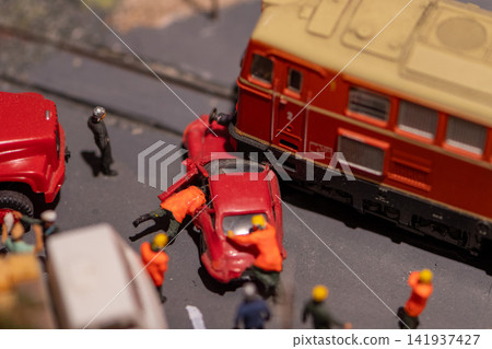 Miniature train crash scene with rescue workers surrounding damaged red car Miniature train crash scene with rescue workers surrounding damaged red car 141937427
