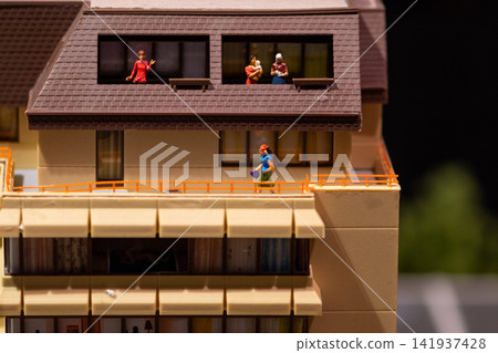 Miniature residential building model with tiny figures on balconies and walkway Miniature residential building model with tiny figures on balconies and walkway 141937428