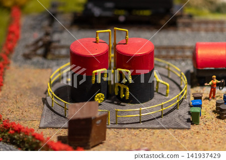 Closeup of miniature industrial storage tanks with railings on model terrain Closeup of miniature industrial storage tanks with railings on model terrain 141937429